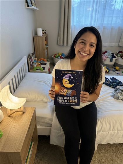 Mom on her child's bed holding Book 1
