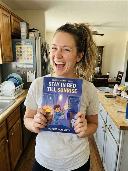 Excited mom holding Book 3 in the kitchen