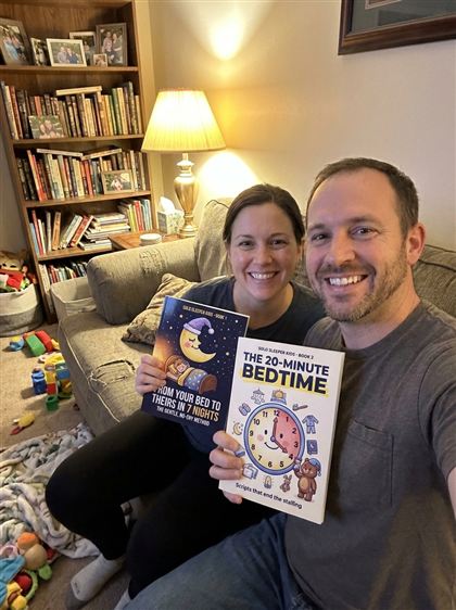Parents on the couch holding Book 1 and Book 2